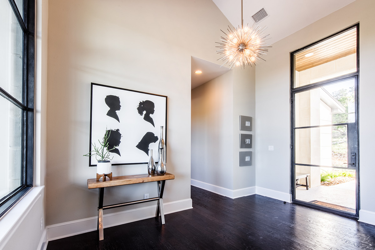 3911-2 Modern farmhouse entryway with glass door, silhouette artwork, and contemporary chandelier.
