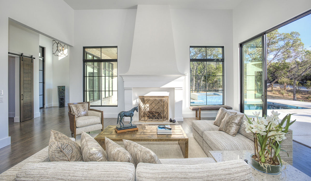4030-5 Spanish Revival kitchen with high ceilings, large island, and tall windows next to a dining area featuring wood ceiling beams and wrought iron chandelier.