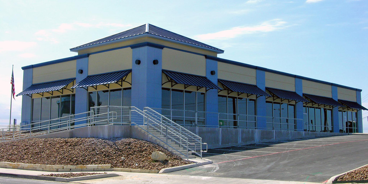 agora - Completed Agora Place retail shell building featuring multiple storefronts, blue awnings, and exterior stair access.