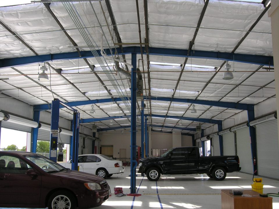Interior of autobody shop with high ceilings, service bays, and multiple cars under repair
