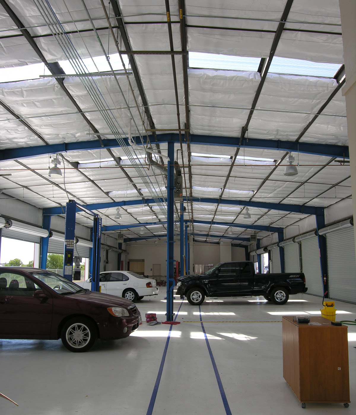 autobody - Interior of autobody shop with high ceilings, service bays, and multiple cars under repair