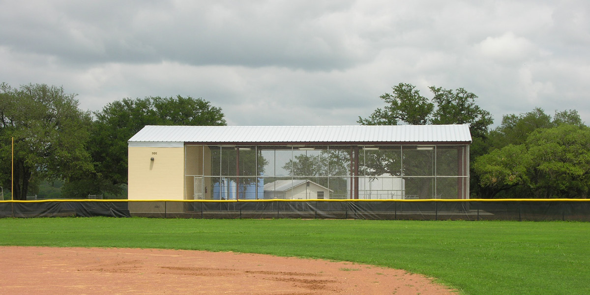 Side view of Bandera ISD softball field batting practice facility and dugout.