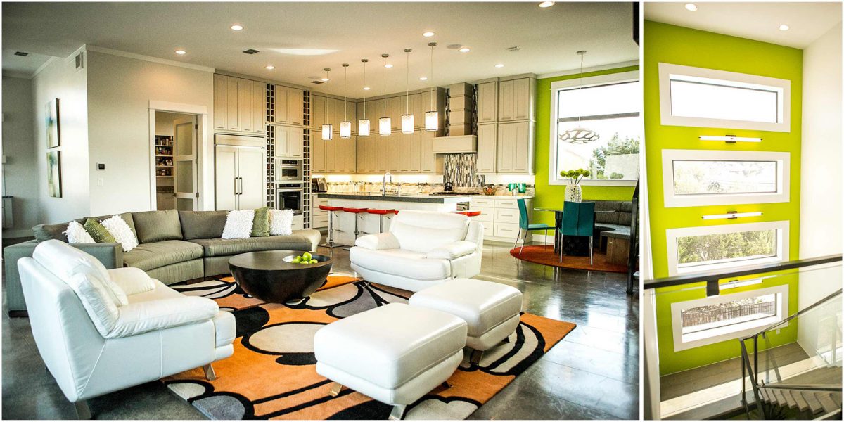 Open-concept modern living room with bold patterned rug, white leather chairs, and a sleek kitchen featuring pendant lighting and red barstools, accented by a vibrant green wall with stacked windows.