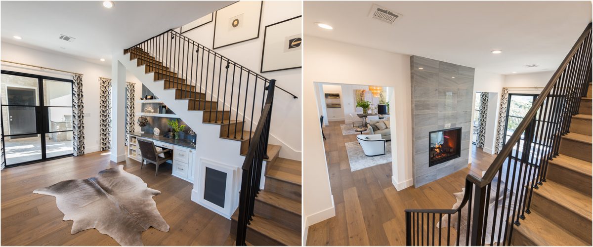 3674-11 Contemporary home interior with a staircase featuring black iron railings, built-in desk nook, hardwood floors, and a sleek double-sided fireplace leading into the living room.