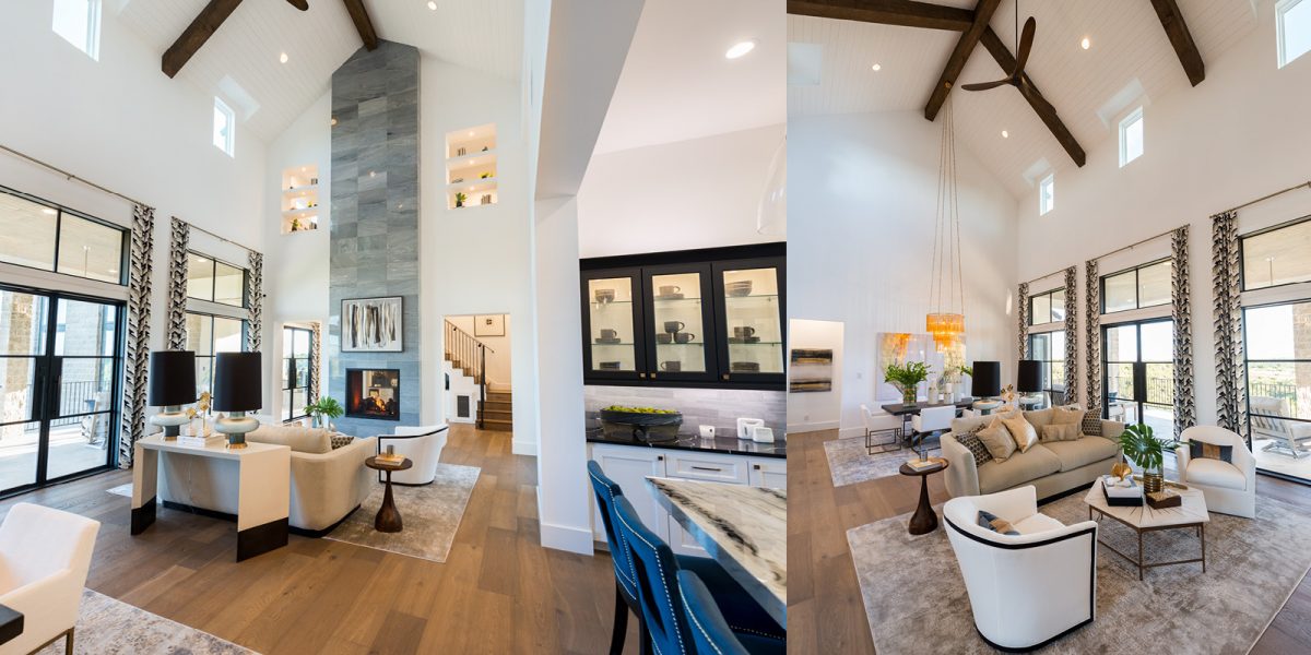 Bright living room with tall ceilings, exposed beams, and a floor-to-ceiling stone fireplace, featuring large windows and modern seating.
