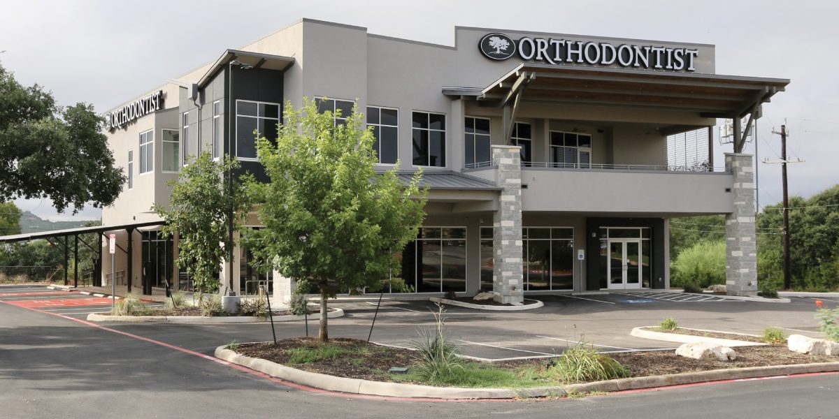 NORRIS SHELL - Exterior view of Norris MOB, a modern two-story medical office building in San Antonio with orthodontist signage, large windows, and stone accents.