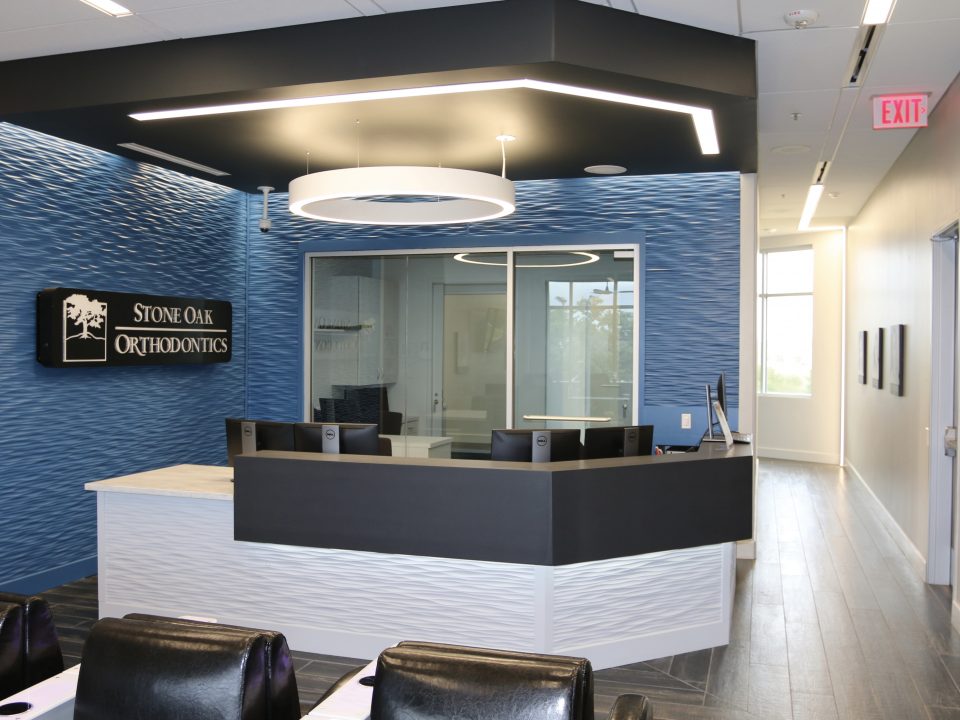 Front desk reception area with Stone Oak Orthodontics signage and modern lighting