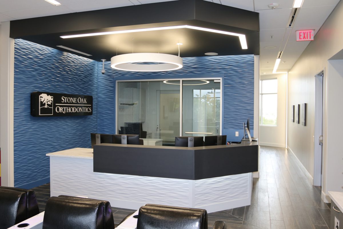 Front desk reception area with Stone Oak Orthodontics signage and modern lighting